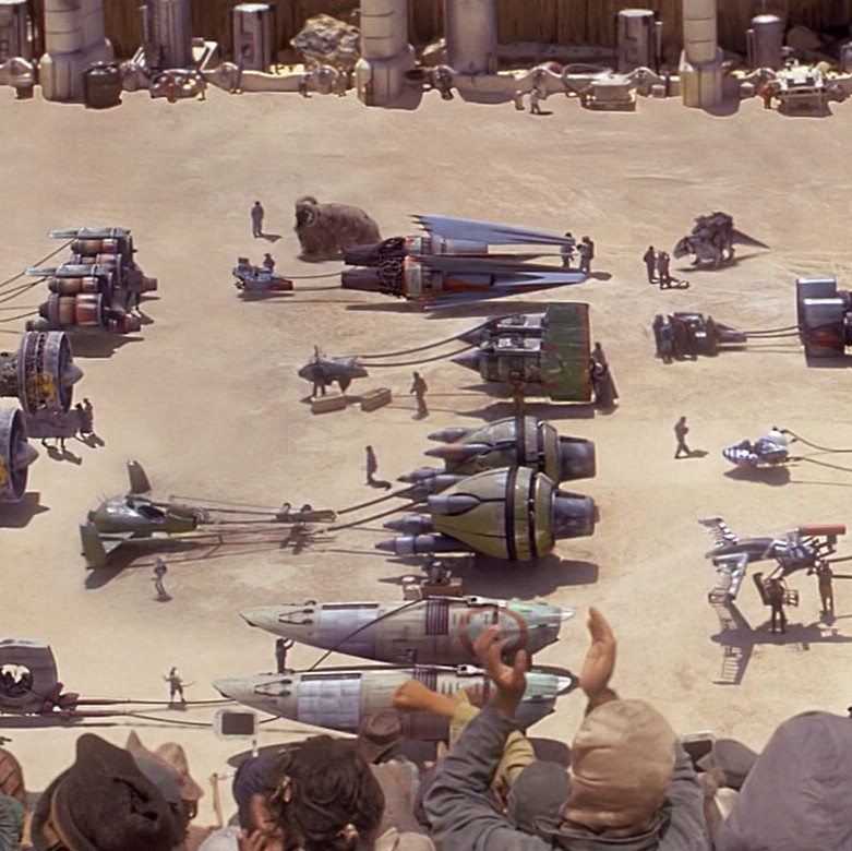 Podracers lined up at the start line for a race